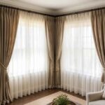Beżowe zasłony i białe firany przy narożnych oknach w eleganckim salonie